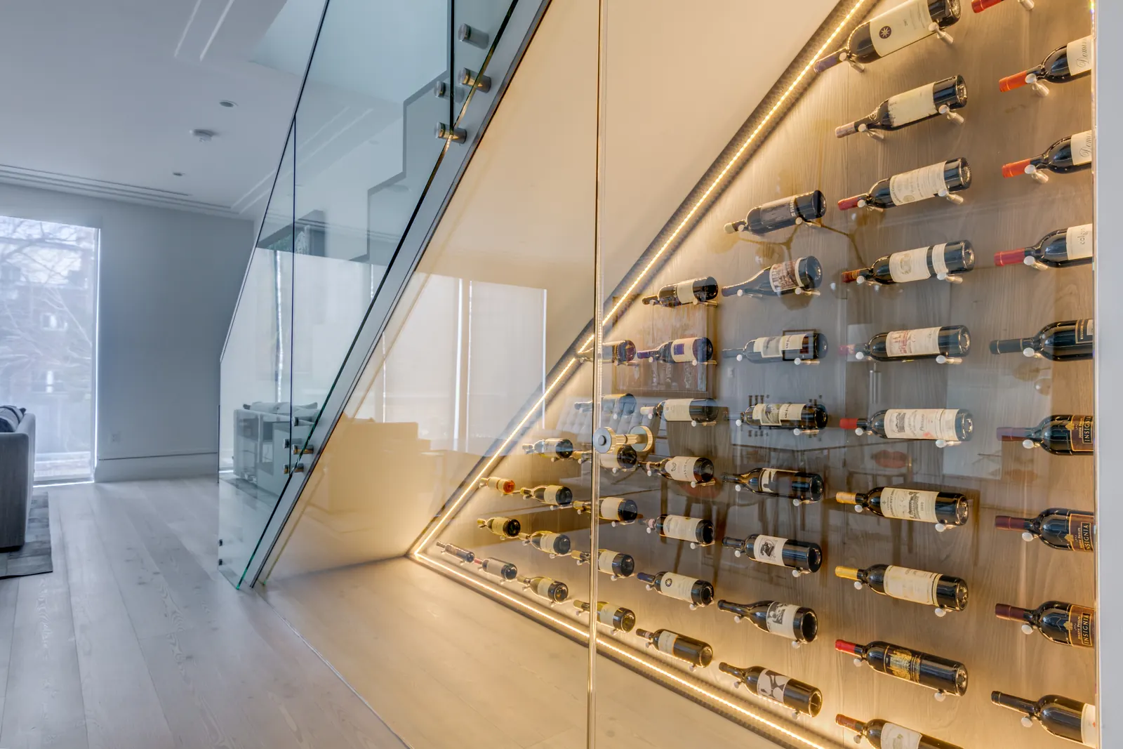 Display-forward wine wall treating bottles as art, with slim metal supports presenting labels against an illuminated feature panel